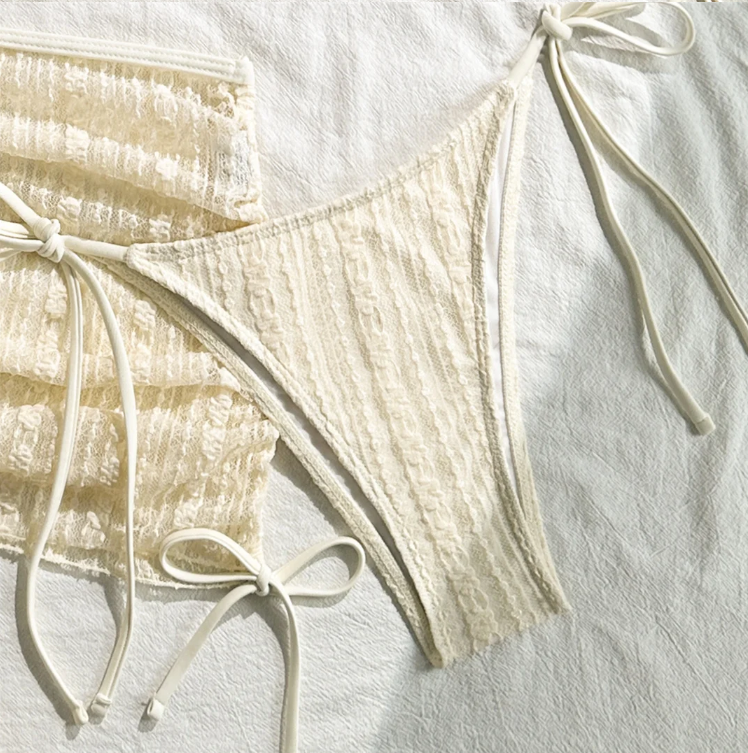 Close-up of Amalfi cream textured bikini bottoms with matching sheer mini skirt and adjustable side ties.
