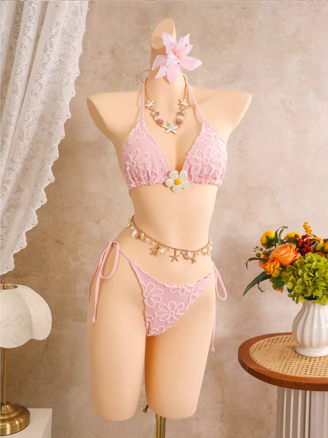 Pink floral embroidered triangle bikini set with flower centre accent, shell-inspired styling and tie-side bottoms on mannequin.