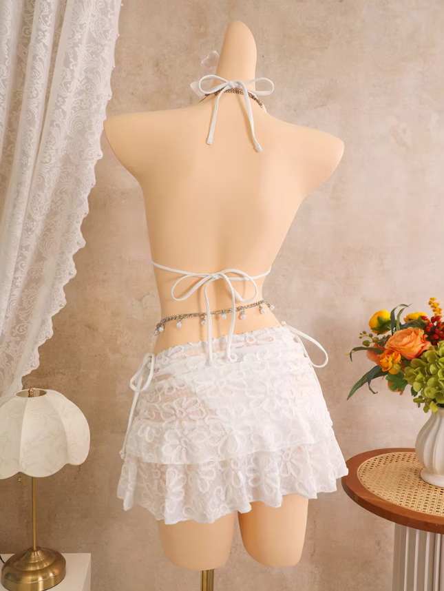 Back view of white floral embroidered bikini and sheer mini skirt set with halter tie, back tie and layered skirt.