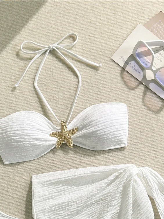 Close-up of white textured bandeau bikini top with halter neck strap, starfish centre detail and matching sarong.