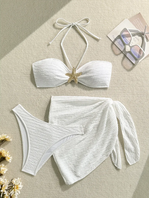 White textured bandeau bikini and matching tie sarong set with starfish centre detail in a flat lay.