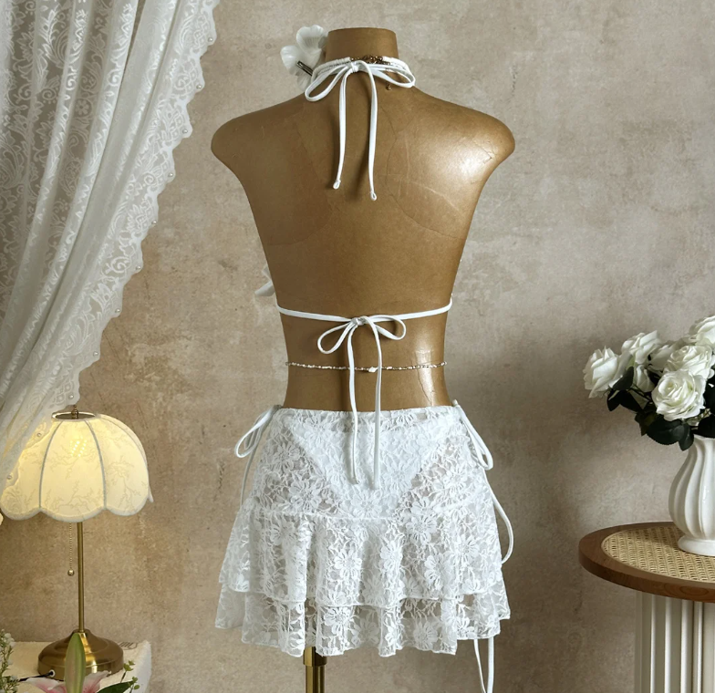 Back view of Bondi white bikini and lace mini skirt set displayed on mannequin with halter ties and tiered skirt.
