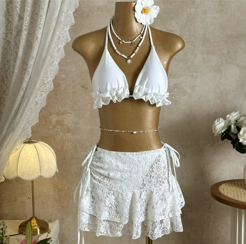 Bondi white bikini and lace mini skirt set displayed on mannequin with frill triangle top and tiered floral skirt.