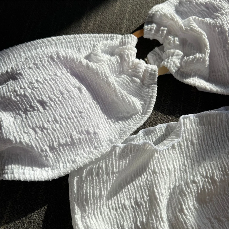 Close-up of Boracay white textured swim fabric with ruched sarong detail and gold-tone ring hardware.