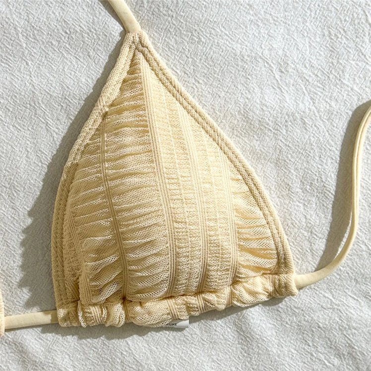 Close-up of ivory textured triangle bikini top with halter ties and gathered cup detailing.