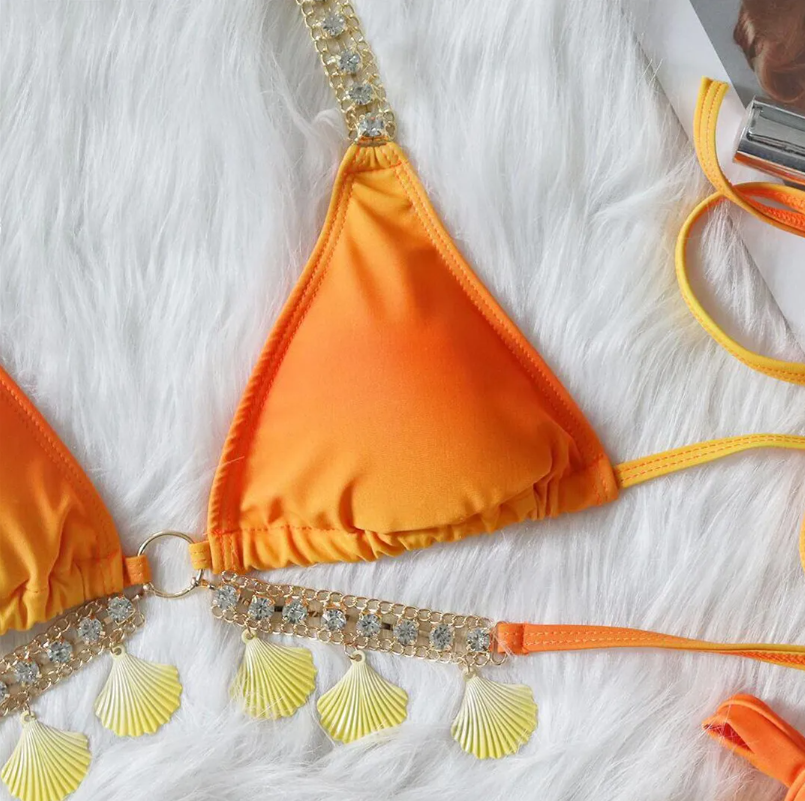 Close-up of Cancún orange triangle bikini top with rhinestone halter straps and dangling shell charm trim.