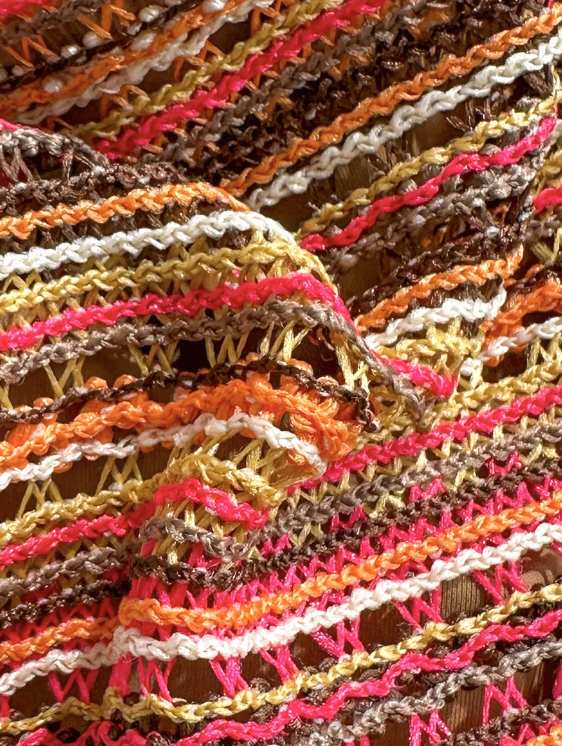 Close-up of textured striped bikini fabric in brown, cream, orange and pink tones.