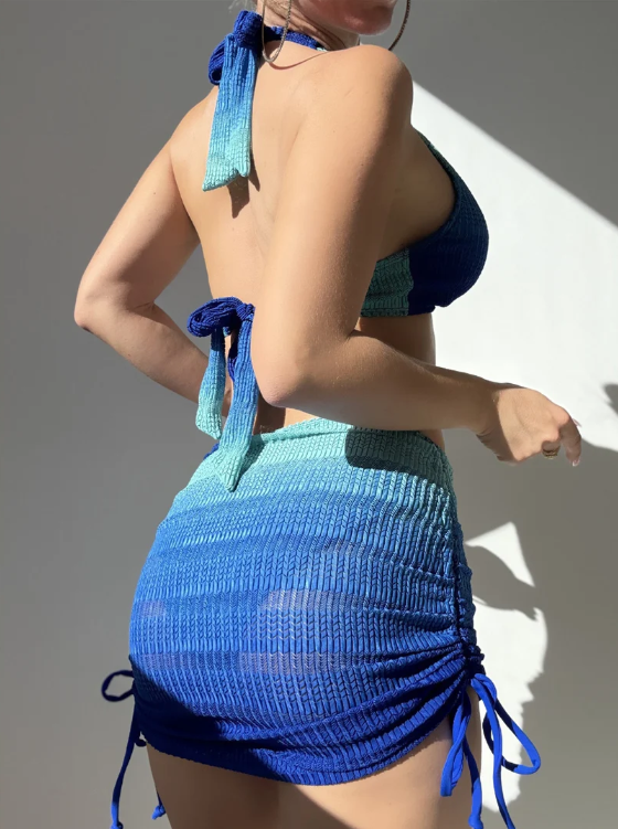 Side back view of Copacabana blue ombré bikini and ruched mini skirt set with tie-back halter top and adjustable skirt ties.