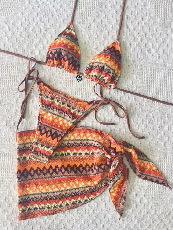  Flat lay of the Curaçao Bikini Set featuring a triangle bikini top, tie-side bottoms and matching wrap sarong in a zigzag stripe pattern.