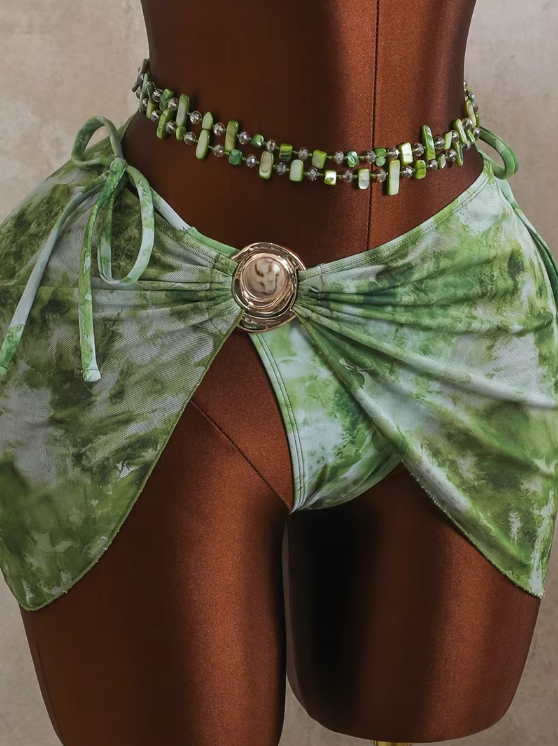 Close-up of CURATOR Collection Capri green bikini bottoms and matching sheer sarong with gold-tone shell ring hardware.