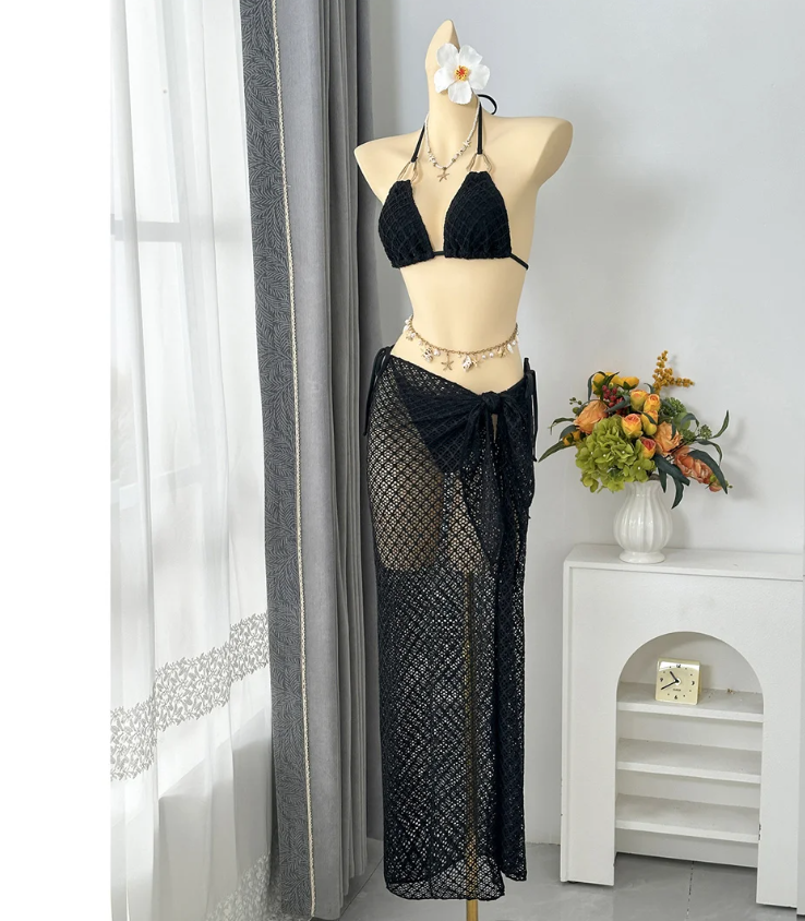 Angled front view of black textured halter bikini set with sheer openwork maxi sarong.