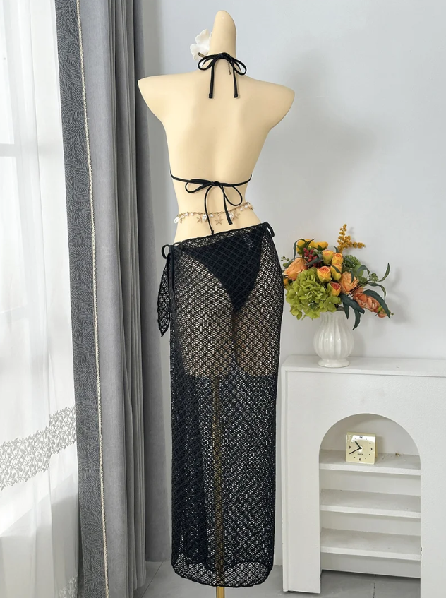 Back view of black openwork bikini and maxi sarong set with halter tie and back tie fastening.
