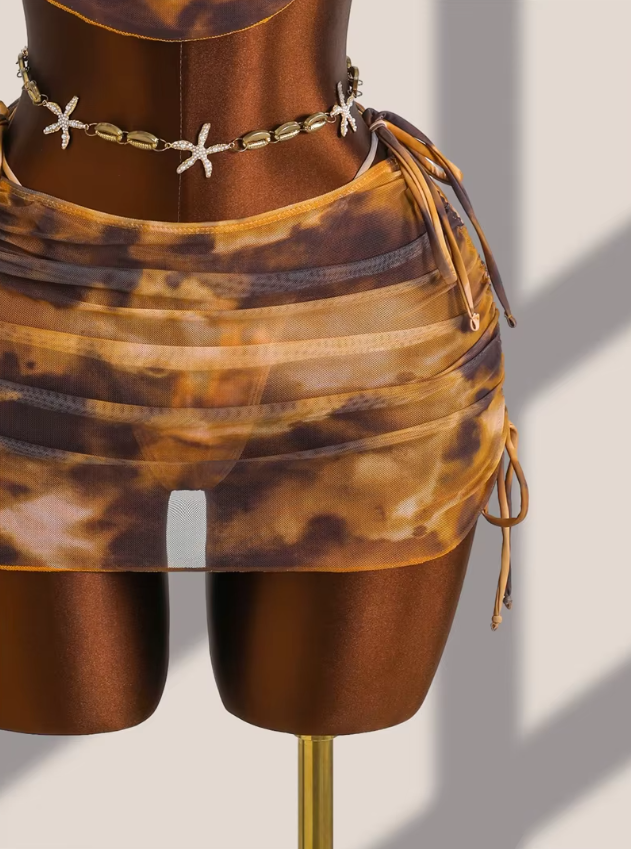 Close-up of the Moonstone sheer tie-dye mini skirt overlay with ruched side ties and matching bikini underneath.