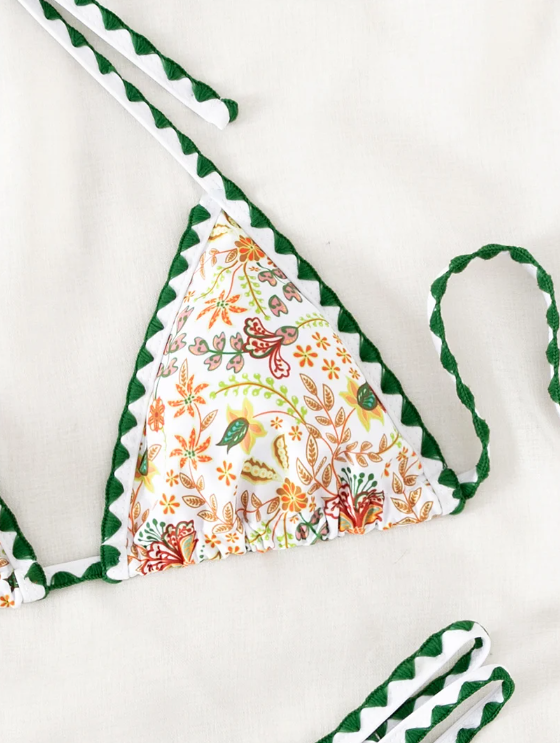 Close-up of white botanical floral bikini top with deep green contrast trim halter ties.