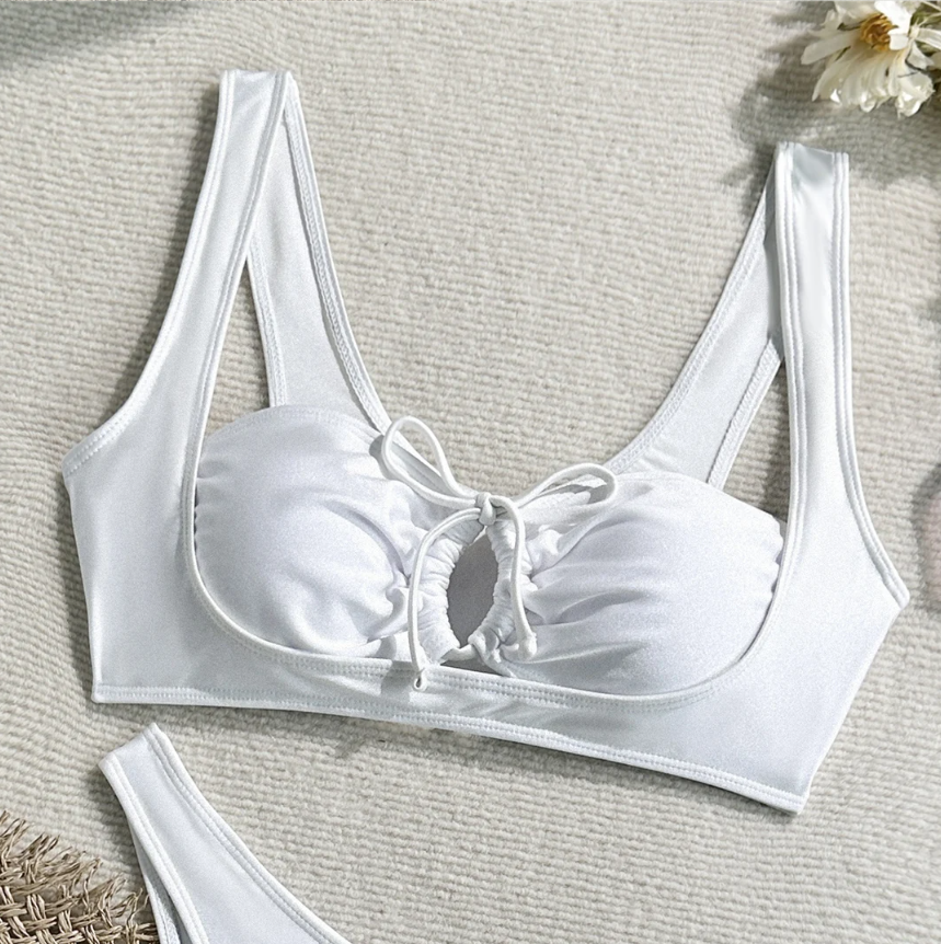 Close-up of white longline bikini top with wide straps, gathered cups and lace-up centre front detail.