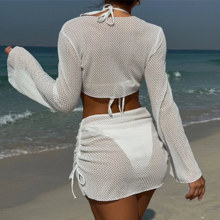 Back view of white bikini and matching mesh cover set with long-sleeve top and ruched mini skirt.
