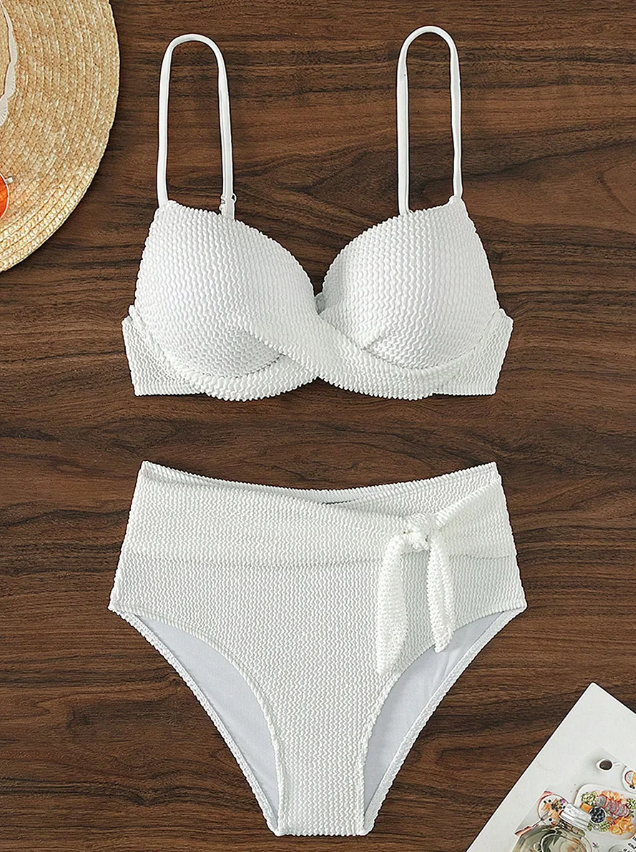 Flat lay front view of white textured bikini set with twist-front underwired top and high-waisted bottoms with bow detail.
