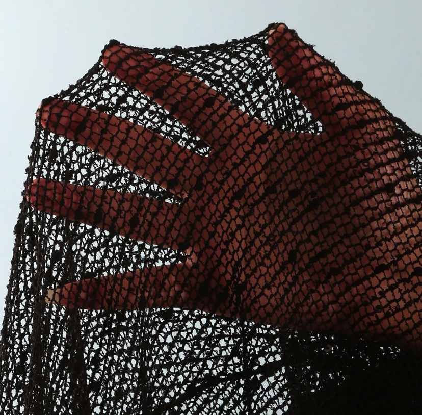 Close-up of black sheer openwork mesh fabric with textured resort finish.