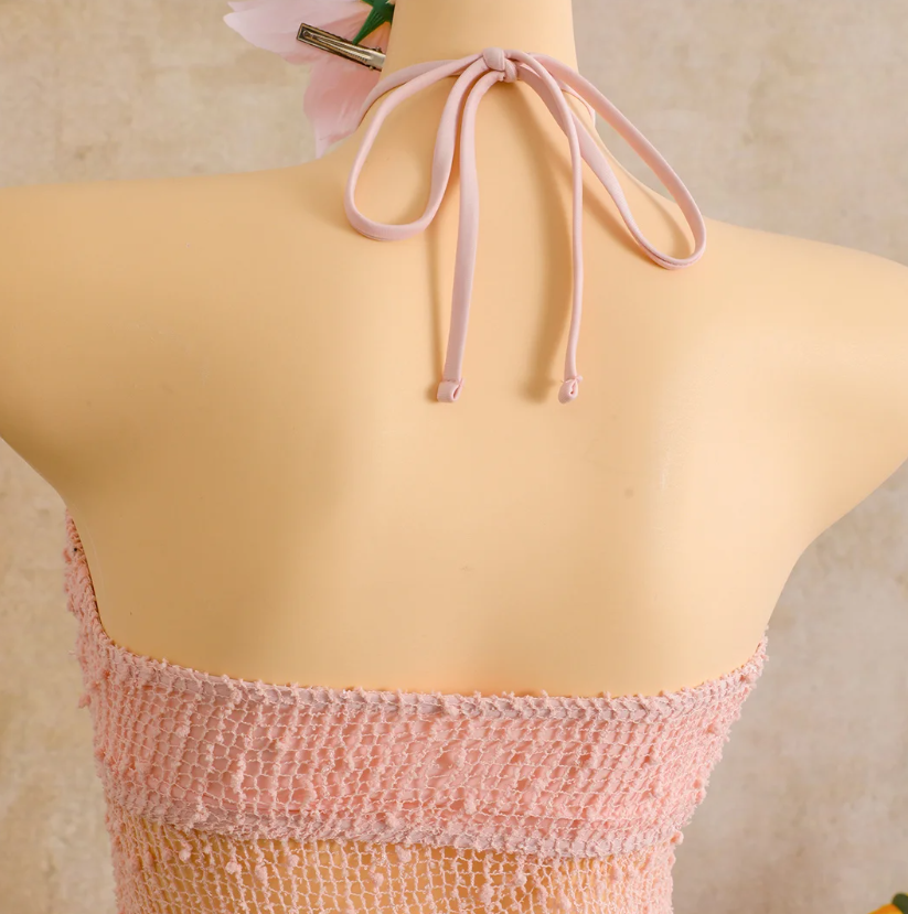 Close-up of camellia halter neck tie on sheer openwork resort dress.