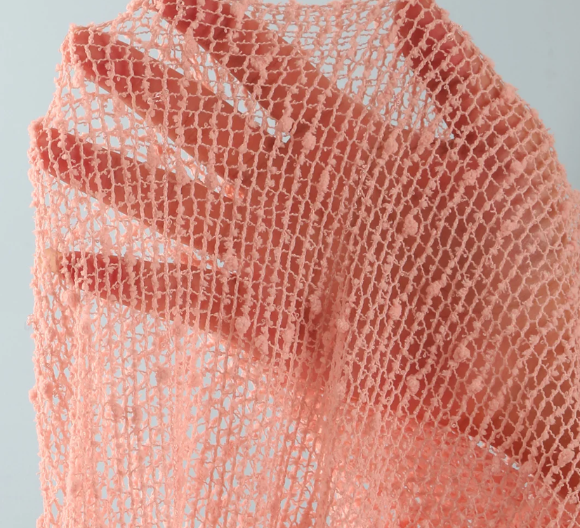 Close-up of camellia sheer openwork mesh fabric with textured raised details.