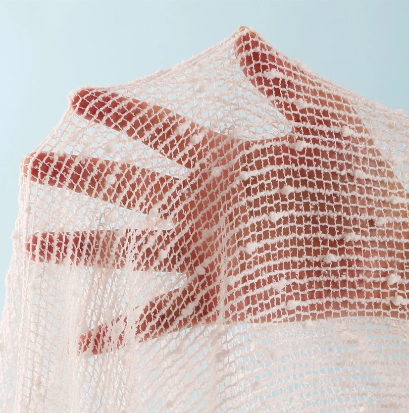 Close-up of ivory sheer openwork mesh fabric with textured raised details.