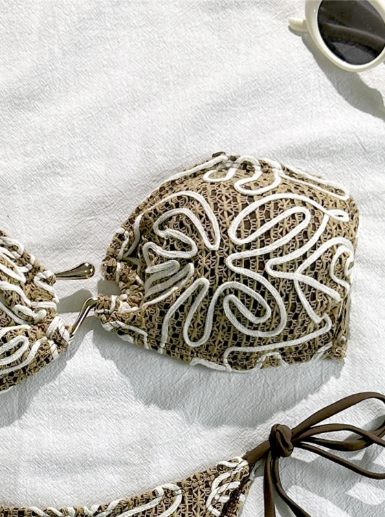 Close-up of brown crochet-look bandeau bikini top with raised cream cord embroidery and gold-tone centre hardware.