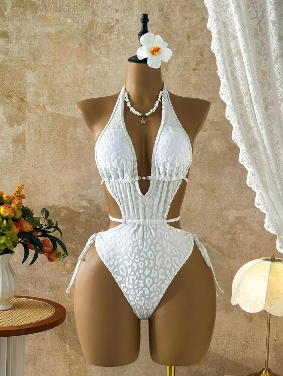 Front view of white tonal leopard one-piece swimsuit displayed on mannequin with plunging neckline, bead hardware and side waist cut-outs.