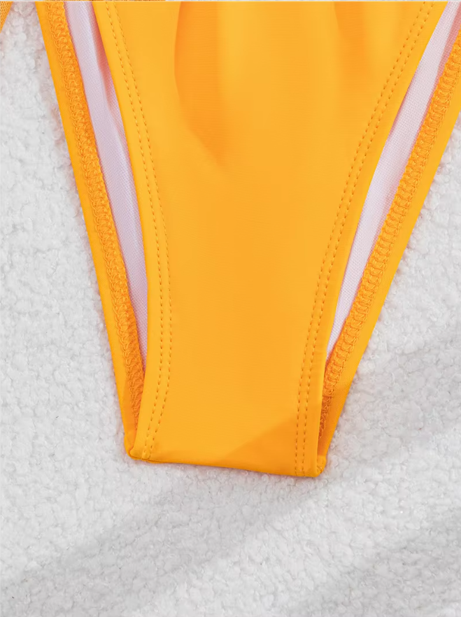 Close-up of bright orange bikini bottoms showing smooth swim fabric, lined interior and clean stitched edges.