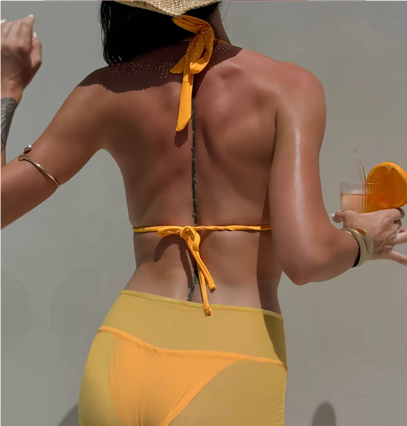 Back view of orange bikini and sheer mini skirt set with halter tie, back tie and lightweight skirt overlay.