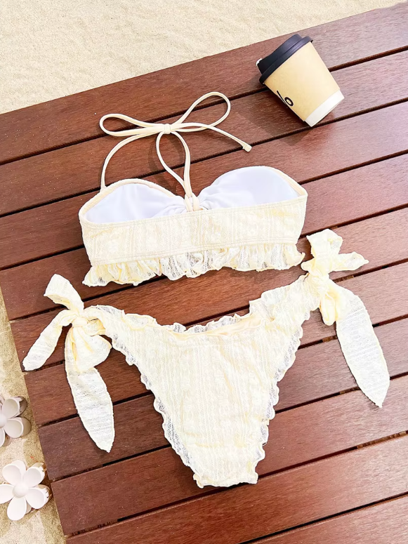 Ivory textured bikini set flat lay with halter bandeau top, ruffle trim and oversized side-tie bottoms.