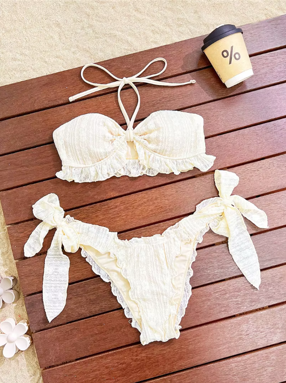 Libre ivory bikini set flat lay with ruffle-trim bandeau top and oversized bow tie bikini bottoms.