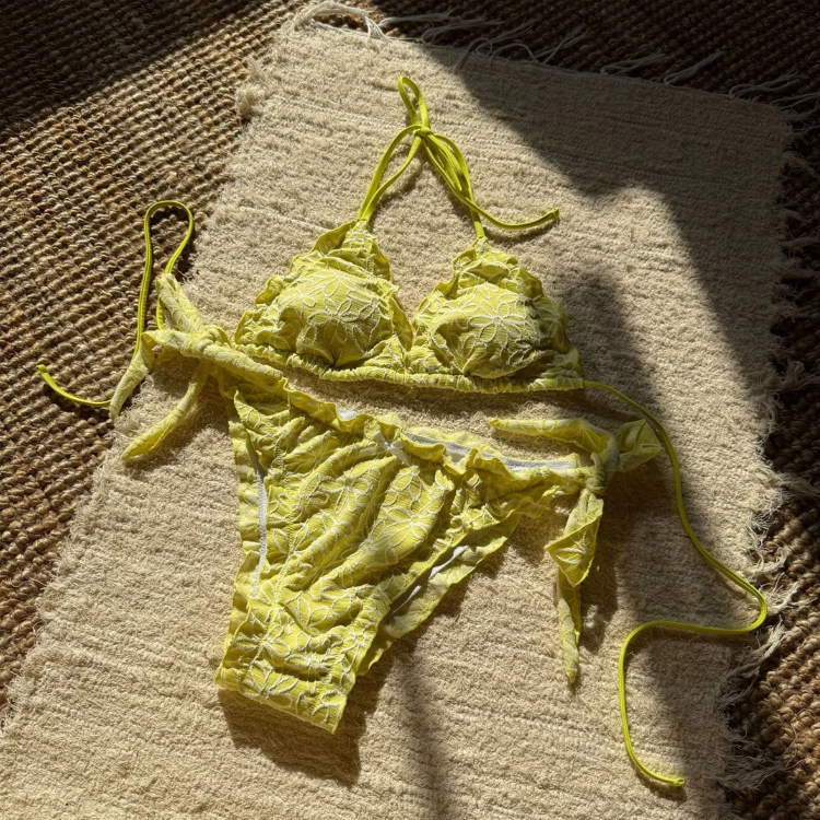 Limoncello yellow floral bikini set flat lay with triangle halter top, ruffle trim and tie-side bottoms.
