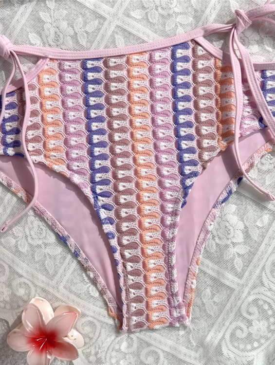 Close-up of pastel crochet-look high-waisted bikini bottoms with pink side ties and soft lining.