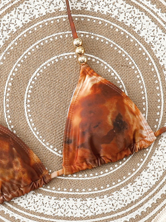 Close-up of amber marbled triangle bikini top with halter tie, gathered cup and gold-tone bead detail.