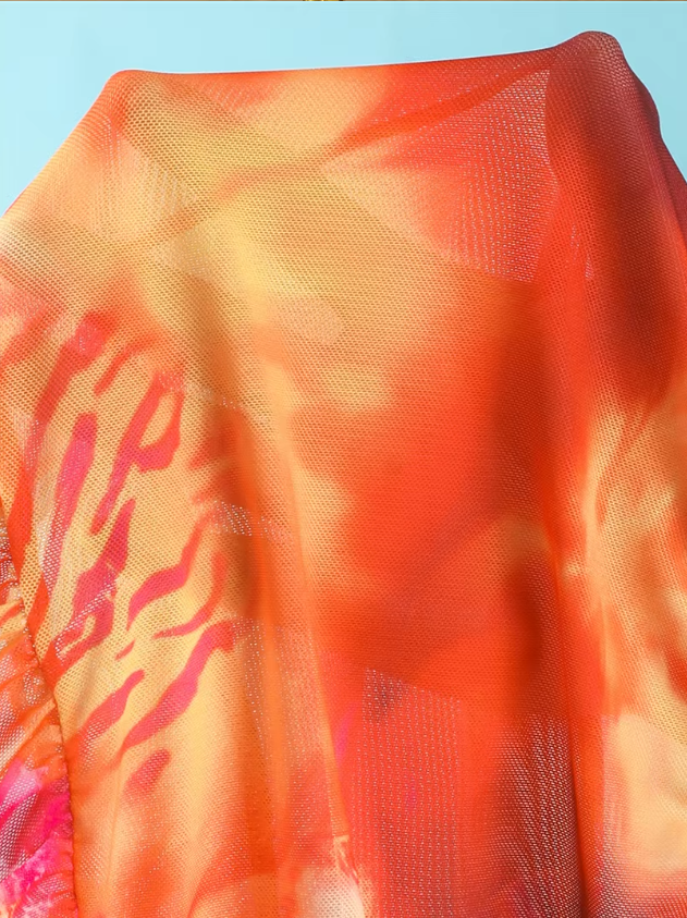 Close-up detail of Marbella orange mesh fabric showing the sheer sunset print material.