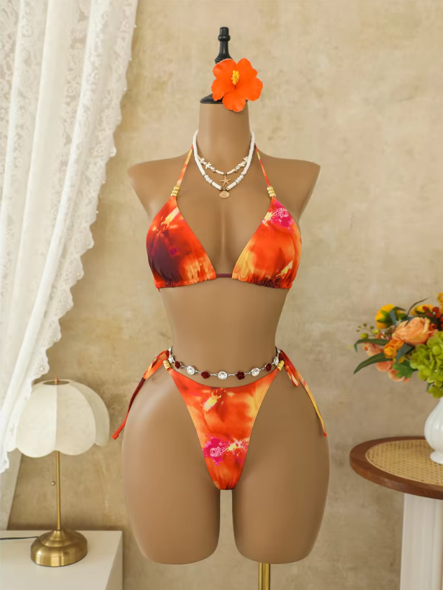 Marbella orange bikini set displayed on a mannequin with triangle halter top, tie-side bottoms and beaded waist detail.
