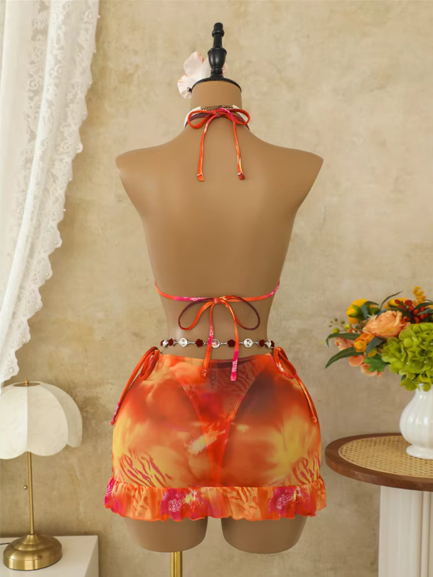 Back view of Marbella orange bikini and skirt set on a mannequin with halter tie top and sheer ruffle-hem skirt.
