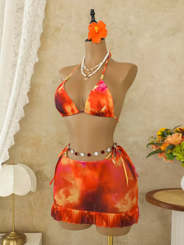 Marbella orange bikini and skirt set displayed on a mannequin with triangle top, sheer mini skirt and ruffle hem.