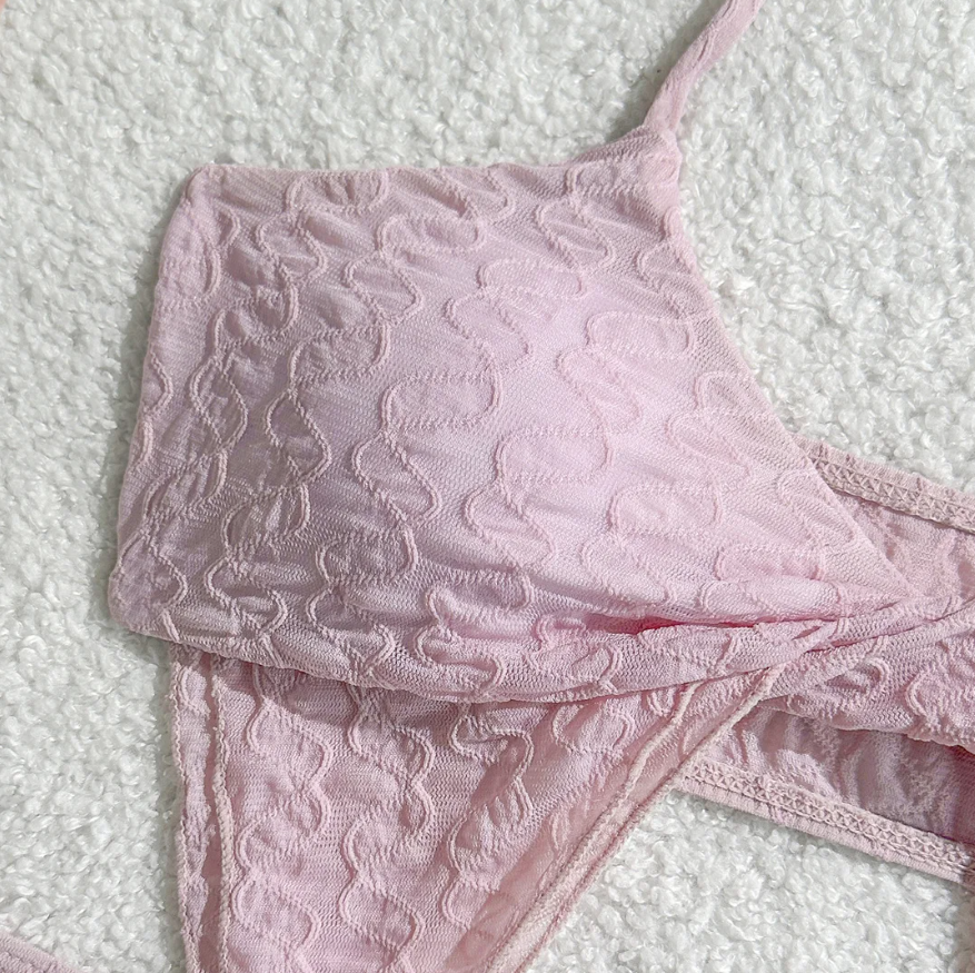 Close-up of Maya pink textured halter bikini top with twist-front detail and cut-out silhouette.