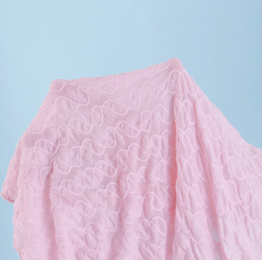 Close-up of Maya pink textured swim fabric showing soft raised abstract pattern.