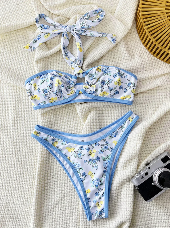 Mykonos floral bikini set flat lay with bandeau-style halter top, sky-blue contrast binding and high-leg bikini brief.
