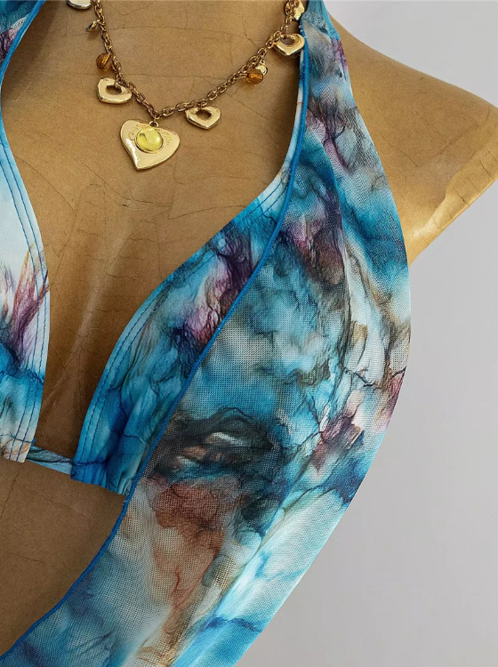 Close-up of blue watercolour marble fabric with sheer draped halter top detail and soft ocean-toned print.