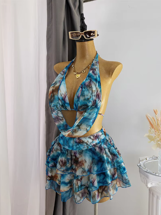 Angled front view of blue watercolour resort set with draped scarf-style halter top and layered ruffle mini skirt.