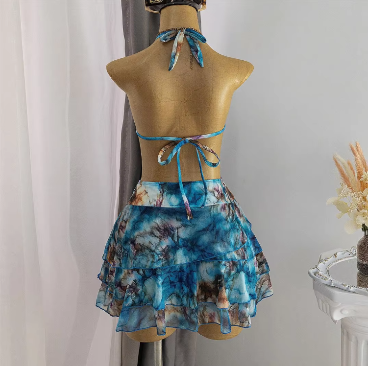 Back view of blue watercolour bikini and layered mini skirt set with halter tie, back tie and ruffle skirt detailing.