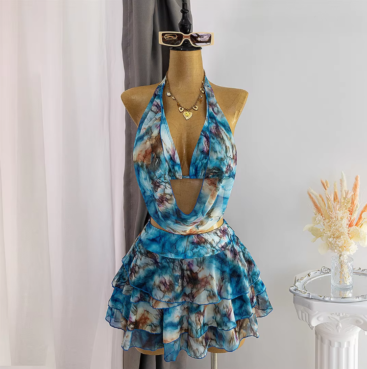 Front view of blue watercolour bikini and layered mini skirt set with scarf-style halter top and flowing ruffle hem.