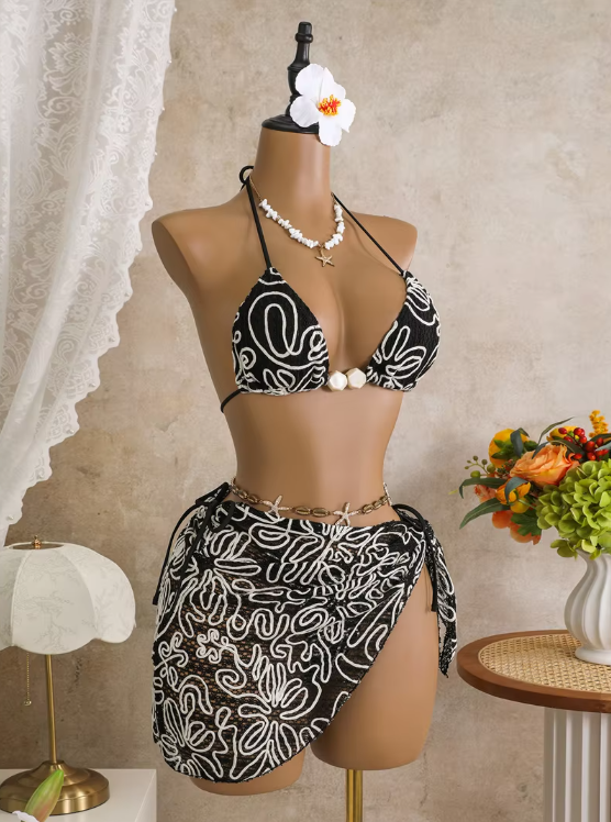 Angled front view of black embroidered bikini and wrap sarong set with triangle halter top and contrast floral cord detailing.