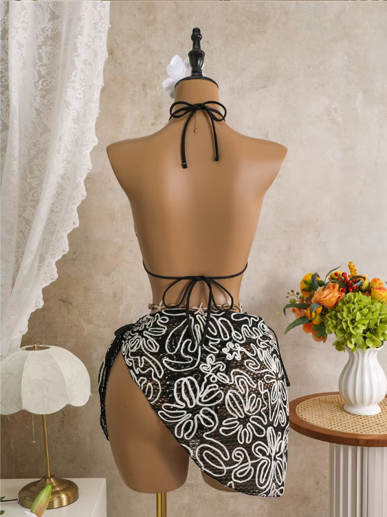 Back view of black corded floral bikini and wrap sarong set with halter tie, back tie and asymmetric sarong drape.