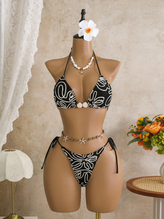 Black corded floral triangle bikini set with contrast white embroidery, shell-inspired centre beads and tie-side bottoms.