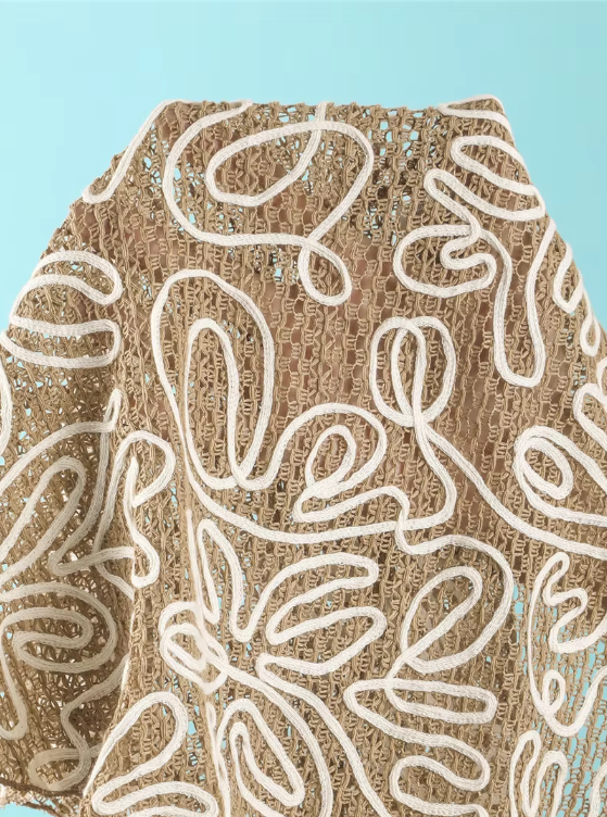 Close-up of Cocoa Shell openwork fabric with raised white corded floral embroidery and textured resort finish.
