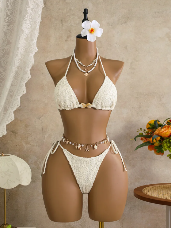 White corded floral triangle bikini set with shell-inspired centre beads and tie-side high-leg bottoms on mannequin.